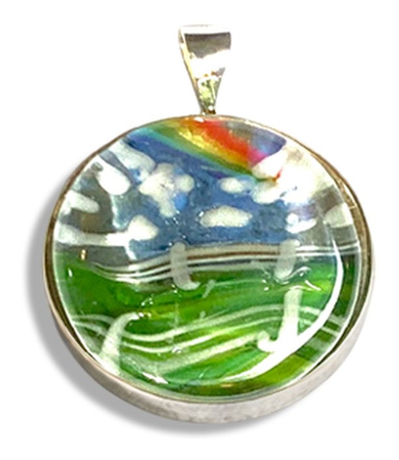 A round bezel set pendant with a glass landscape of a rainbow over green fenced hills